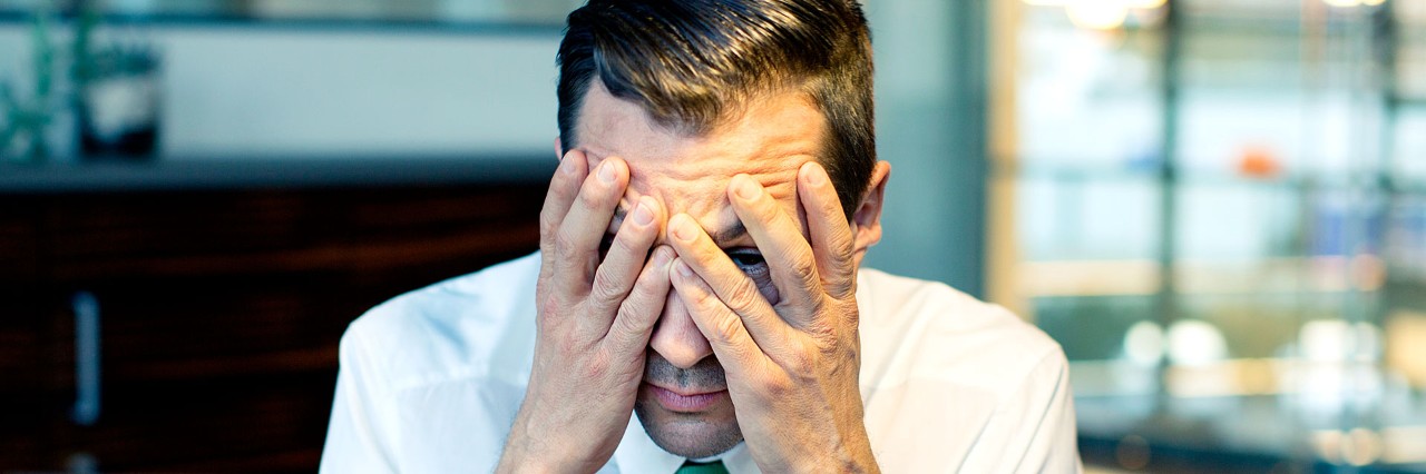 A man with his hands over his head and face, disappointed