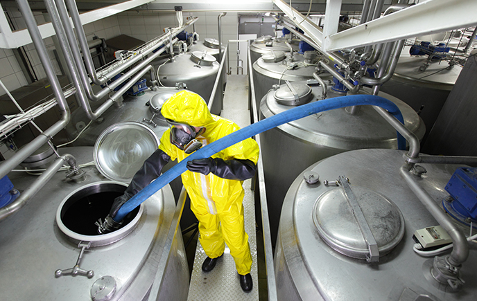 Man in PPE filling chemical vats