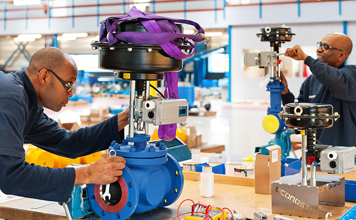 Engineers installing actuator to pump in work shop